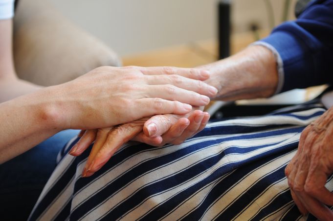 Jüngere Person hält Hände einer älteren Person