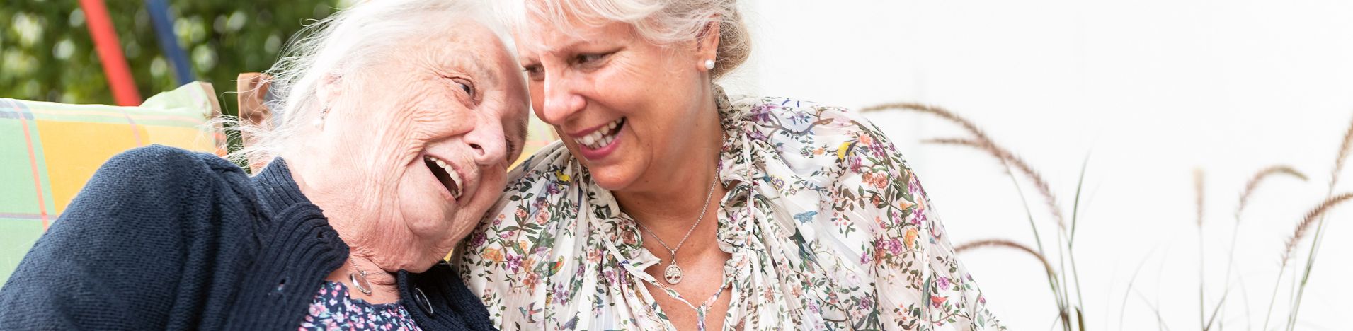Ältere Frau und jüngere Frau lachen und halten Garn und bunte Decke
